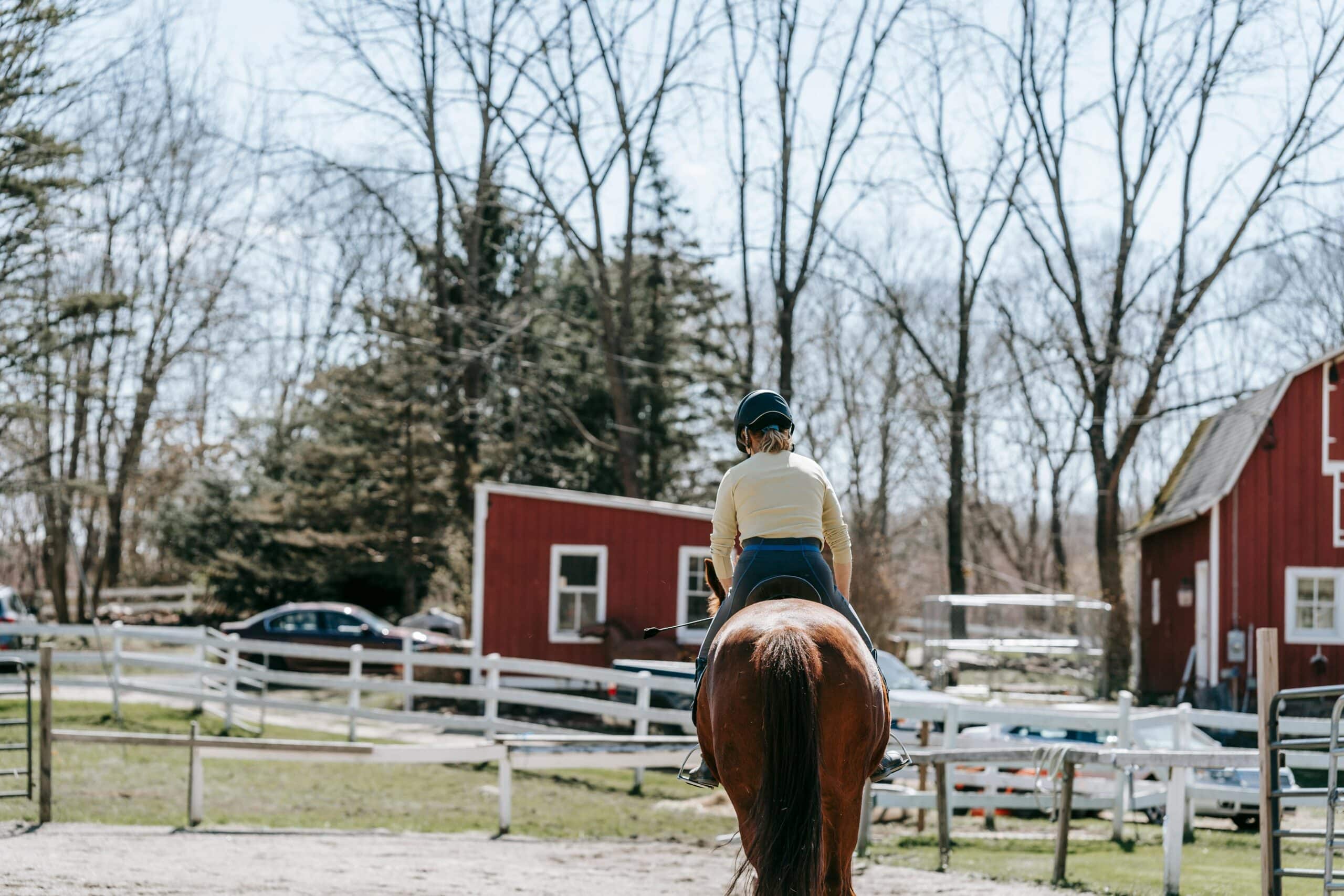 Woman Riding a horse in front of a red barn